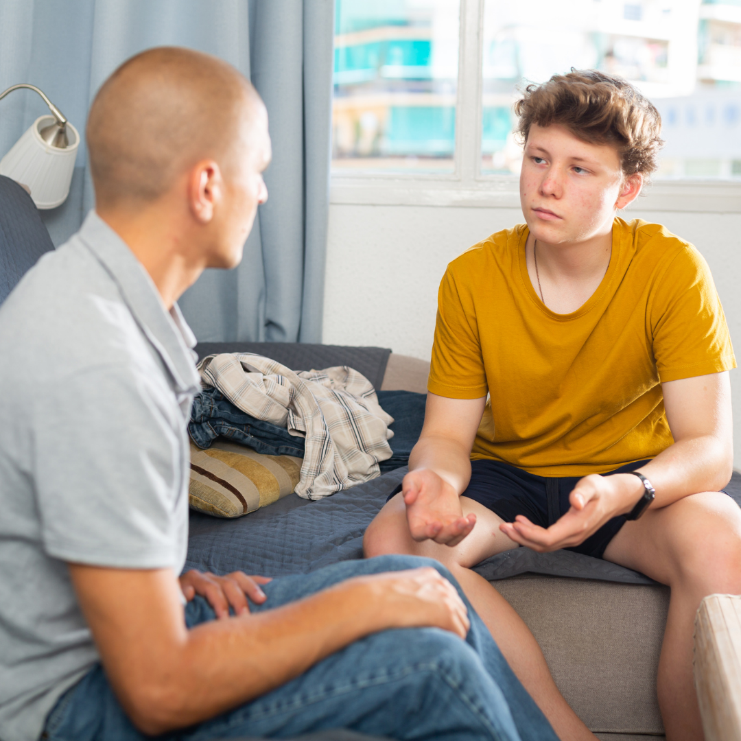 Father talking seriously with teenage son about online safety and boundaries.